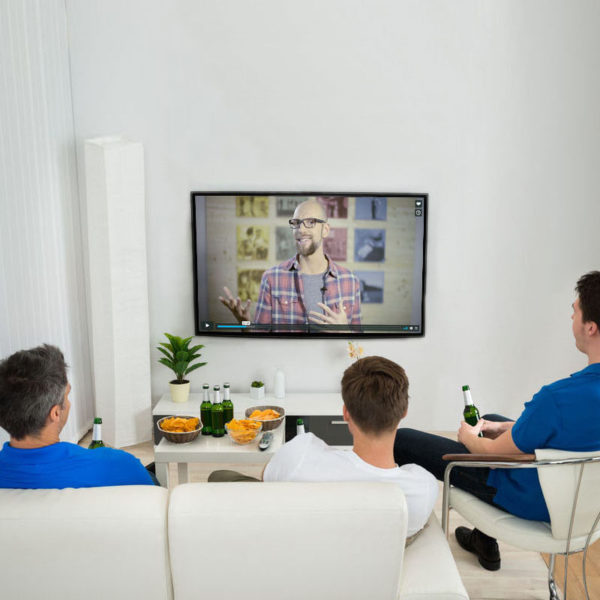 36497979 - three men sitting on couch watching football match on television